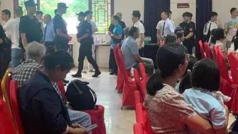 Early Rain Covenant Church Some congregants sitting on chairs while others, mostly men, stand in line to be escorted away by police officers