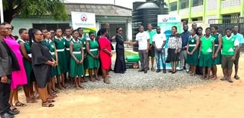 David Amevor (4th from left), Junior Divisional Manager of Asa Savings and Loans, Tema Division, in a handshake with Regina Tetteh, Headmistress, Nungua SHS, after the presentation