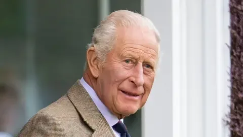 Getty Images A photo of King Charles from the shoulders up. He is wearing a patterned suit jacket with a white shirt and tie. He is looking towards the camera and smiling. The background is blurred.