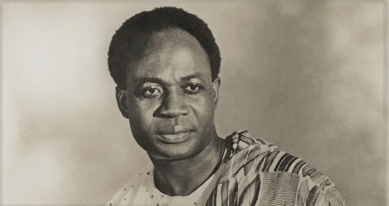 A classic black-and-white portrait of Dr. Kwame Nkrumah, the first President of Ghana. He is depicted wearing traditional Kente cloth over a white garment, looking slightly away from the camera with a serious and thoughtful expression.