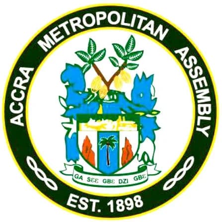 The official logo of the Accra Metropolitan Assembly (AMA) is shown as a circular seal. The emblem features a central crest with a palm tree, cocoa pods, and the Ga motto, all enclosed within a green border stating the assembly's name and founding date.