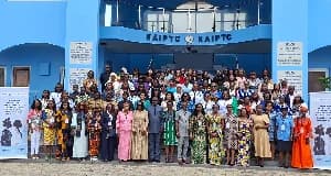 A large group of predominantly female participants pose for a photograph in front of the Kofi Annan International Peacekeeping Training Centre (KAIPTC) in Accra. The attendees, including many in traditional African prints and some in professional uniforms, are gathered for a regional maritime security summit.