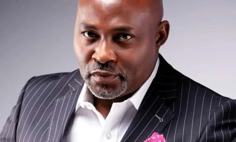 A professional portrait of Richard Mofe-Damijo (RMD), a prominent Nigerian actor. He is seen wearing a black pinstripe suit, a white dress shirt, and a pink pocket square, looking directly at the camera with a serious expression.