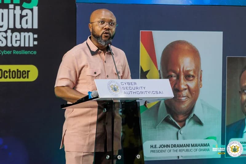 Dr. Albert Antwi-Boasiako, Director-General of Ghana's Cyber Security Authority (CSA), is pictured speaking at a podium during a cybersecurity event. The background features a large portrait of President John Dramani Mahama and text highlighting 'Cyber Resilience' and the month of October.