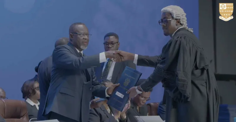 The image shows Ghanaian politician Emmanuel Armah-Kofi Buah shaking hands with a legal official during a Call to the Bar ceremony. Fellow Member of Parliament Sam Nartey George is visible in the background. Both politicians are part of a large group of over 1,500 new lawyers being inducted into the legal profession in Ghana.