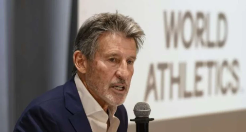 Sebastian Coe, the President of World Athletics, is captured speaking into a microphone during a press event. Behind him, the 'WORLD ATHLETICS' branding is visible on a white background, suggesting an official announcement or conference setting.