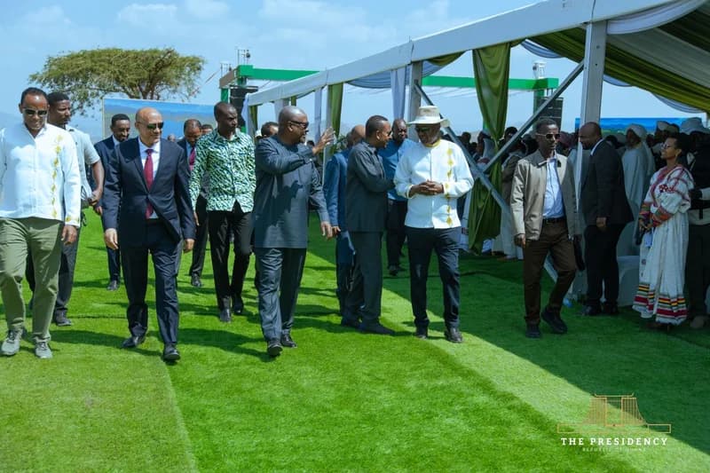 President John Mahama of Ghana is seen walking alongside Ethiopian Prime Minister Abiy Ahmed and other officials during a state visit to Ethiopia. The group is moving across a green lawn toward a large white ceremonial tent structure, likely for the inauguration of the Megech Irrigation Project.