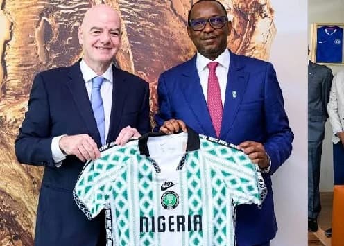 FIFA President Gianni Infantino and a Nigerian official pose together while holding a green and white Nigerian national football team jersey. The two men are dressed in formal business suits, signifying an official meeting between FIFA and Nigerian football representatives.