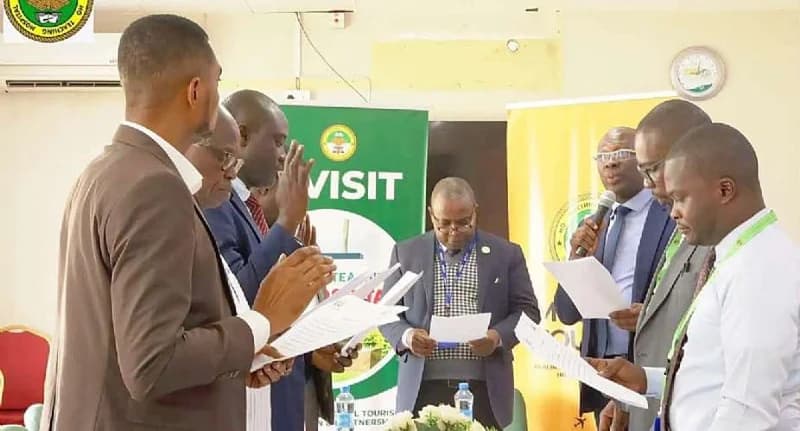 A group of officials at the Ho Teaching Hospital are seen taking an oath during the reconstitution of the hospital's audit committee. The men are dressed in formal business attire, holding documents and raising their hands in a swearing-in ceremony against a backdrop of official hospital banners.