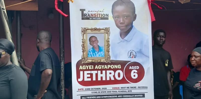 A funeral poster for six-year-old Jethro Agyei Agyapong is prominently displayed, surrounded by mourners in black and red attire. The poster features two photos of the young boy and provides details for his final funeral rites scheduled for October 2026 in Nkyeraa.