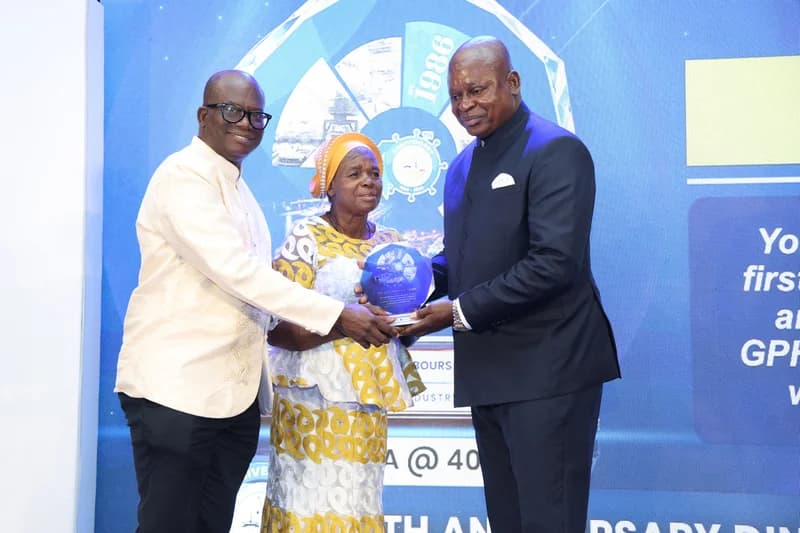 Ghana's Minister for Transport, Kwaku Ofori Asiamah, along with another official, presents an honorary award plaque to an elderly woman. The ceremony takes place in front of a blue backdrop celebrating a 40th anniversary for the Ghana Ports and Harbours Authority (GPHA).
