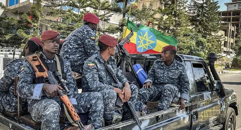 A group of Ethiopian security personnel in camouflage uniforms and red berets are seen sitting in the back of a patrol vehicle. One soldier holds a scoped rifle while an Ethiopian flag is displayed prominently on the truck, which is marked with the word 'SWAT'. The scene suggests a heightened security presence in an urban area.