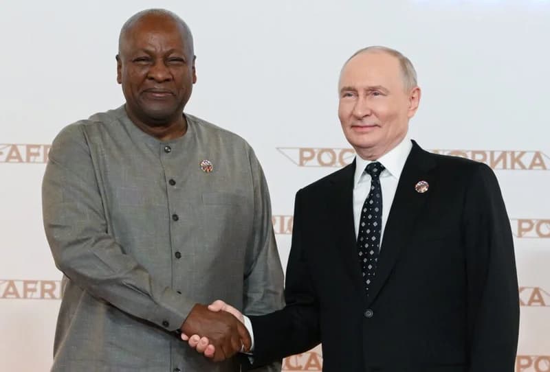 President John Mahama of Ghana shakes hands with Russian President Vladimir Putin during a high-level diplomatic meeting. The backdrop features branding for the Russia-Africa Summit, signifying bilateral cooperation and international relations.
